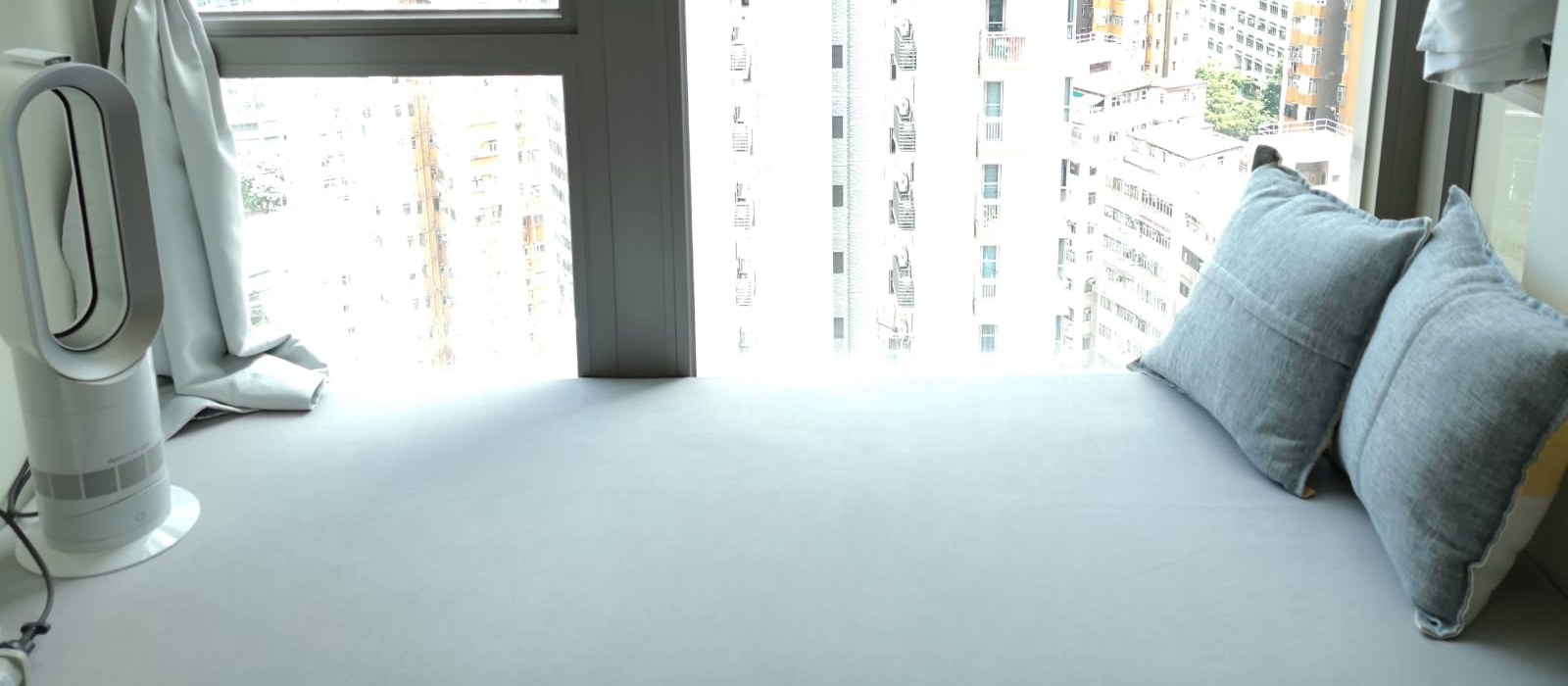 Light grey custom cushion on a city-view window sill